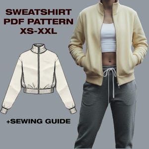Op de afbeelding: Een crèmekleurige sweatshirt met ritssluiting, hoge kraag en voorzakken. De afbeelding toont ook een lijntekening van de sweatshirt en de tekst "SWEATSHIRT PDF PATTERN XS-XXL +SEWING GUIDE."