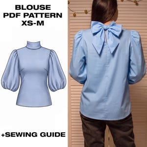 Può includere: Una camicetta azzurra con maniche a sbuffo e scollo alto, mostrata come illustrazione digitale e indossata da una persona. Il retro presenta un grande fiocco sul collo. Testo: BLOUSE PDF PATTERN XS-M +SEWING GUIDE.