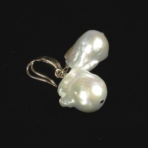May include: A pair of gold earrings with large, white baroque pearls. The pearls are irregular in shape and have a high luster.