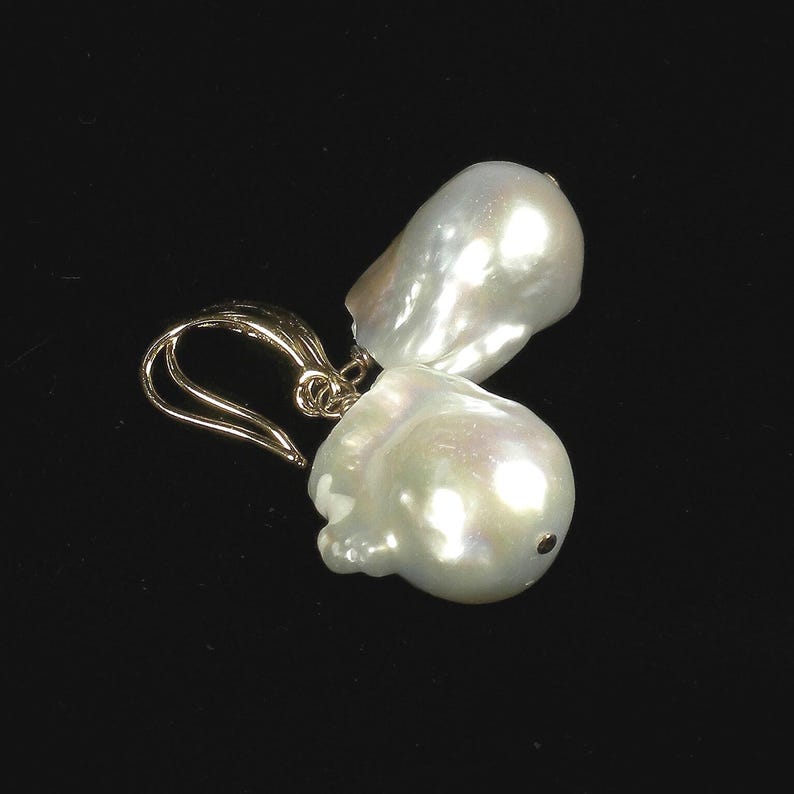 May include: A pair of gold earrings with large, white baroque pearls. The pearls are irregular in shape and have a high luster.