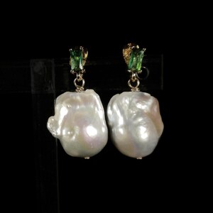May include: A pair of earrings featuring large, white baroque pearls with green gemstone accents.