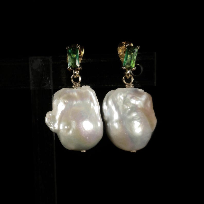 May include: A pair of earrings featuring large, white baroque pearls with green gemstone accents.
