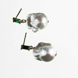 May include: A pair of earrings with large, irregular white pearls and green rectangular stones.