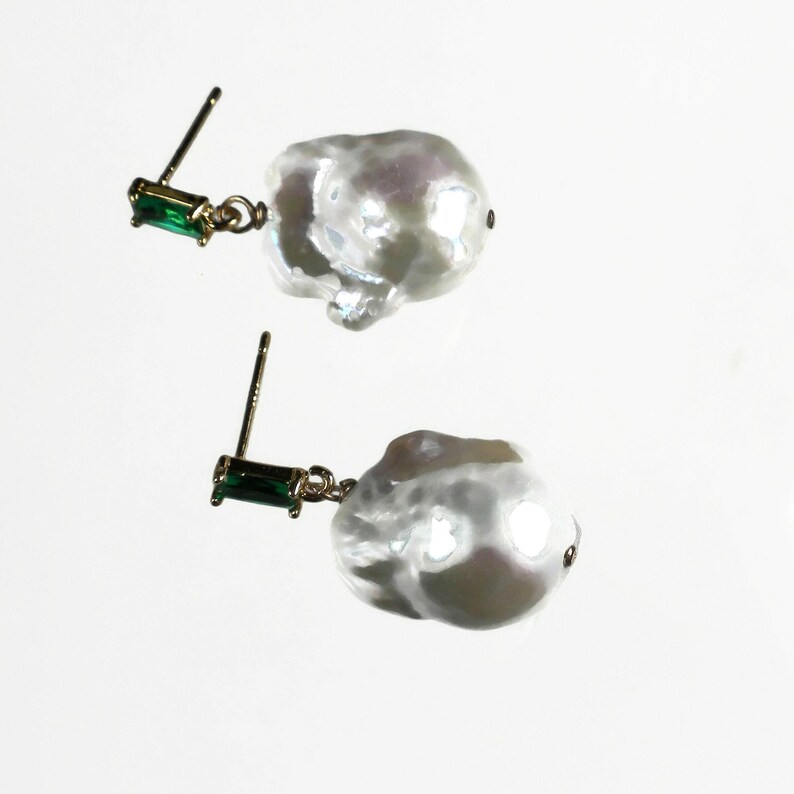 May include: A pair of earrings with large, irregular white pearls and green rectangular stones.