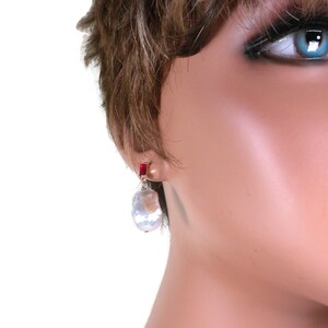 May include: A pair of earrings featuring a large, white baroque pearl with a red gemstone accent.