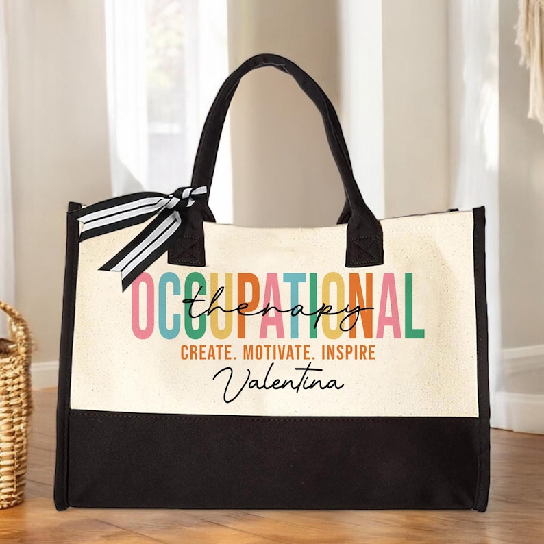 May include: A black and white canvas tote bag with a colorful "Occupational Therapy" design. The text "Create. Motivate. Inspire" is printed below the design, and the name "Valentina" is written in cursive below the text.