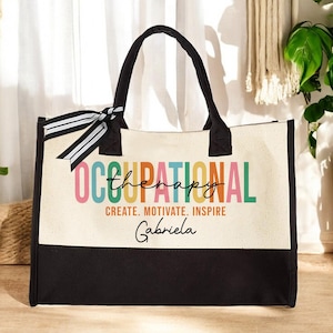 May include: A black and white canvas tote bag with a colorful graphic that says "Occupational Therapy" and "Create. Motivate. Inspire."  The bag also has a personalized name, "Gabriela", in black script.