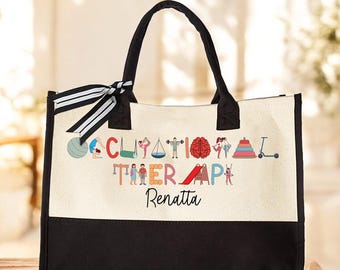 May include: A black and white canvas tote bag with the words "Occupational Therapy" spelled out in colorful letters with small illustrations of children playing. The name "Renatta" is printed below the words.