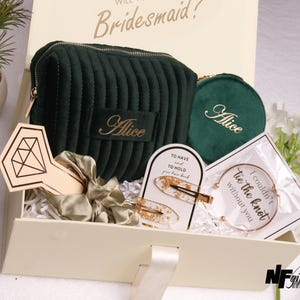 May include: A gift box containing a green velvet cosmetic bag and compact, both embroidered with "Alice". Also includes a gold-toned bracelet, hair clips, and a hair tie. The box has the text "Will you be Bridesmaid?"