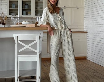 May include: A white pajama set with a floral print. The top has a tie at the neckline and the pants have a wide leg and a ruffle at the bottom.