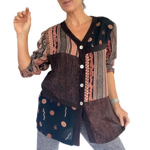 May include: A long-sleeved button-up shirt with a patchwork design. The shirt is made of a soft, lightweight fabric and features a variety of colours and patterns, including black, brown, and pink. The shirt has a relaxed fit and a V-neck.
