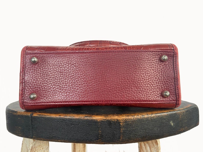 May include: A red leather handbag with a textured crocodile pattern. The bag has silver hardware and a top handle.