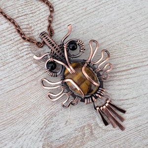 May include: A copper wire wrapped pendant necklace featuring a tiger's eye gemstone and black onyx accents.