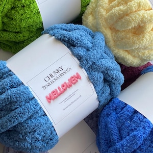 Pode incluir: Close-up de vários novelos de fio de chenille grosso em várias cores, incluindo verde, azul e amarelo. Cada novelo tem uma etiqueta branca com o texto "CHUNKY ŽENILKOVÁ PRIADZA MELLOWEM". O fio parece macio e felpudo.