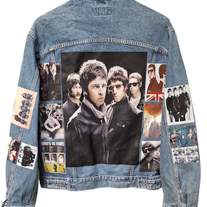 May include: Light blue denim jacket featuring a large black and white image of a band on the back. Additional smaller images and text patches are also present. The jacket has a classic collar and button closures.