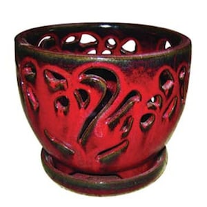 May include: Red ceramic planter with a decorative cutout design and a matching saucer. The planter has a distressed finish and is perfect for adding a touch of rustic charm to your home.