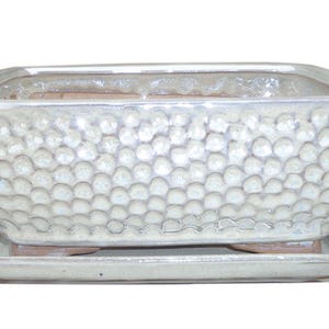 May include: A white ceramic rectangular planter with a textured, raised dot pattern. The planter has a matching saucer.