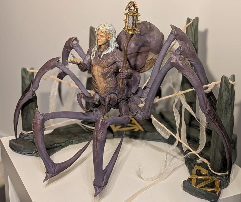 May include: A detailed fantasy figurine depicting a humanoid figure with long white hair, riding a large purple spider-like creature. The figure holds a lantern. The base is a stone-like structure with gold accents.