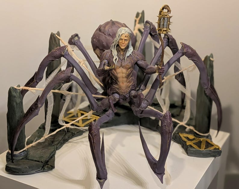 May include: A detailed figurine of a humanoid figure with long white hair, seated on a large, purple spider-like creature. The figure holds a lantern and is set against a backdrop of stone structures and faux spiderwebs. The color palette includes shades of purple, gray, and gold.