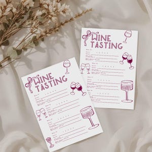 May include: Two white wine tasting scorecards with burgundy text and illustrations. The cards feature the words "Wine Tasting" and include spaces for scoring and notes. Wine glasses are drawn on the cards.