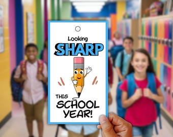 Może przedstawiać: Prostokątna biała zawieszka prezentowa z niebieską obwódką i otworem u góry. Tekst brzmi Looking SHARP THIS SCHOOL YEAR! czarnymi i niebieskimi literami. Na środku znajduje się postać ołówka z kreskówkową twarzą i rękami.