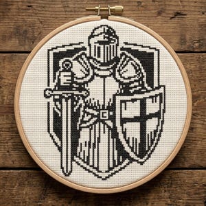 May include: A black and white cross-stitch embroidery of a knight in full armor, holding a sword and shield. The design is set in a wooden embroidery hoop. The knight's helmet, armor, and shield are detailed with cross-stitch patterns.