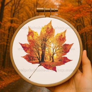 Romantic autumn forest landscape cross stitch inside a maple leaf design - Golden fall leaf embroidery pattern featuring a glowing woodland scene - Nature-inspired autumn decor – maple leaf cross stitch with forest sunlight - Rustic woodland fall embroidery, perfect for cozy seasonal wall art - Detailed maple leaf cross stitch pattern with a warm, romantic autumn theme