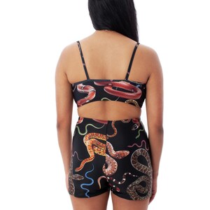 Op de afbeelding: Een zwart tweedelig badpak met een slangenprint. De top is een bandeau-stijl met dunne bandjes. De shorts zijn hoog getailleerd en hebben een brede tailleband.