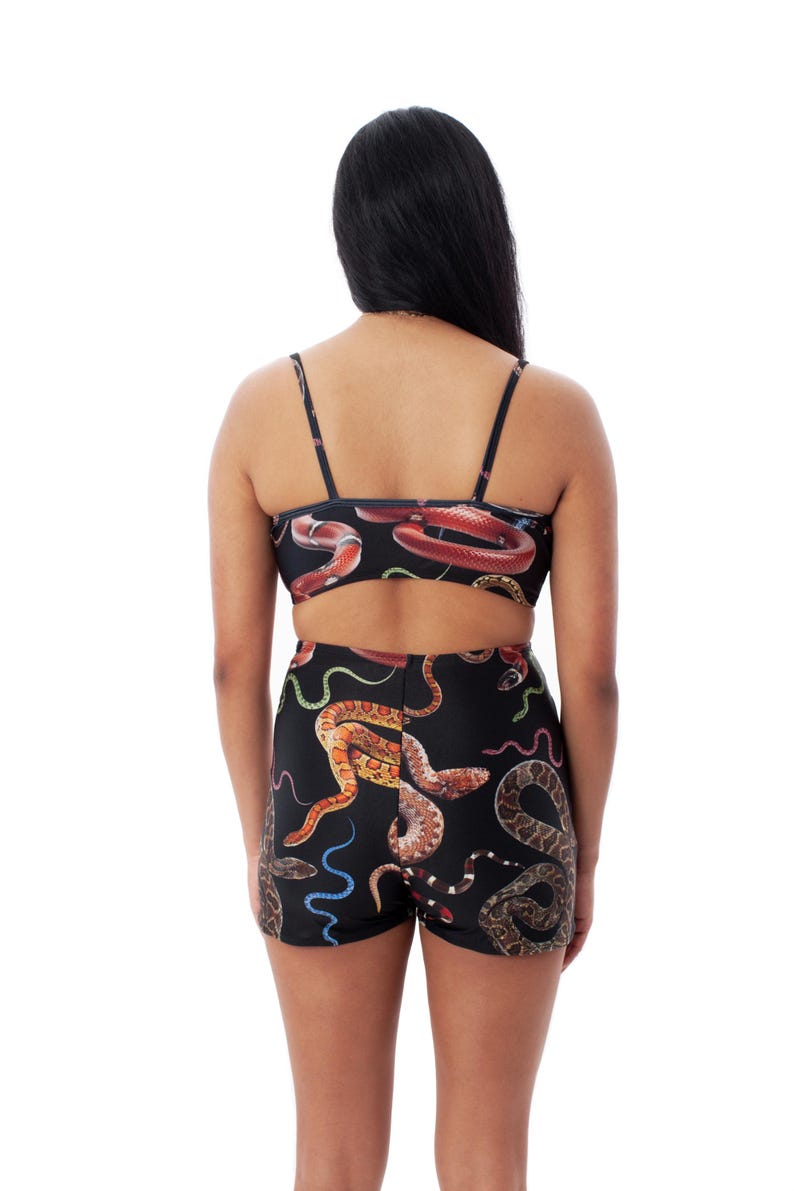 Op de afbeelding: Een zwart tweedelig badpak met een slangenprint. De top is een bandeau-stijl met dunne bandjes. De shorts zijn hoog getailleerd en hebben een brede tailleband.