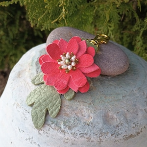 May include: A pink leather flower keychain with a gold metal ring and white pearl accents.
