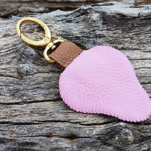 Puede incluir: Un llavero de cuero rosa con una correa de cuero marr&oacute;n y un anillo de metal dorado.