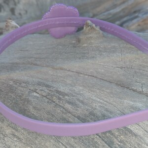 May include: A purple plastic headband with a flower-shaped embellishment.