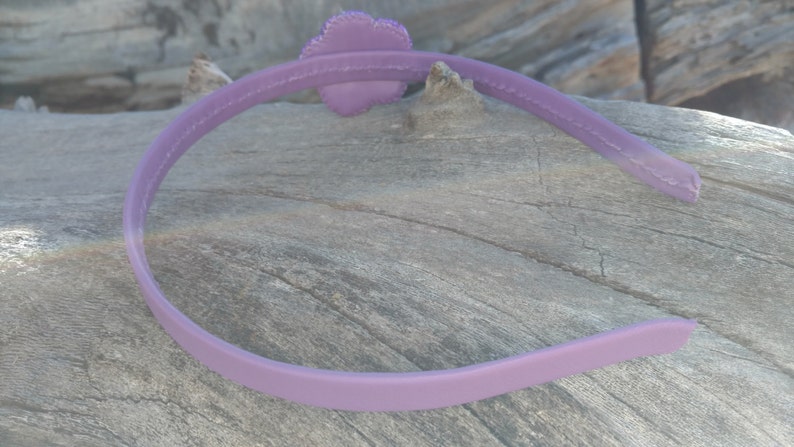 May include: A purple plastic headband with a flower-shaped embellishment.