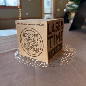 May include: A wooden cube with a QR code and the text "LASER TIME EXCELLENT" and the website address "etsy.com/shop/lasertimeexcellent" on it.