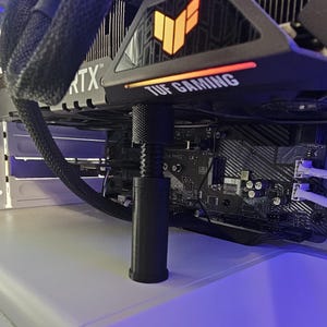 May include: A black graphics card with a black and orange logo that says "TUF GAMING" and the text "RTX" on the side. The card is installed in a computer case and is connected to a motherboard.
