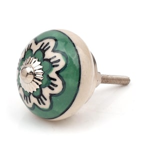 Può includere: Un pomello rotondo in ceramica per mobili con un motivo floreale verde e bianco, dotato di un tappo centrale in metallo argentato e di un perno filettato in metallo che sporge dal retro per il fissaggio su ante o cassetti.