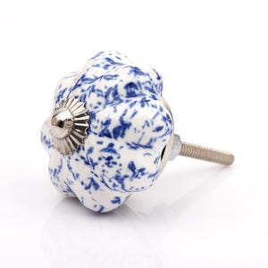 May include: A pumpkin-shaped cabinet knob featuring a white base with a blue speckled floral pattern. The knob has a fluted, rounded design with a metallic silver-coloured centre cap and a threaded metal bolt extending from the back for installation.