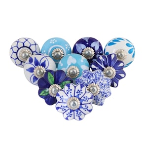 May include: A collection of ceramic cabinet knobs in various floral and patterned designs. The knobs feature shades of blue and white, with silver-toned metal hardware. The designs include floral, polka dot, and abstract patterns, suitable for furniture or decor.