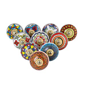 May include: A collection of ten colorful ceramic cabinet knobs with various floral and geometric patterns. Each knob features a gold-toned metal base and a white ceramic surface. The knobs are arranged in a group, showcasing their diverse designs.