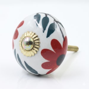 Op de afbeelding: Een witte keramische kastknop met een bloemenontwerp. De knop heeft rode bloemen, blauwgroene bladeren en een goudkleurig midden. De schroefdraad is goudkleurig.