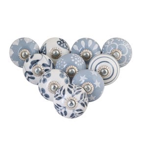 May include: A collection of ten ceramic cabinet knobs in various patterns. The knobs feature designs in white and shades of blue, including floral, dotted, and star patterns. Each knob has a silver-toned metal base.