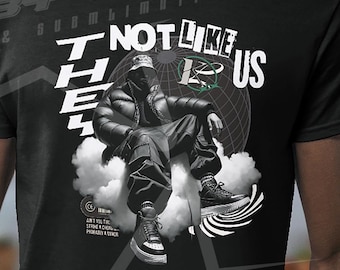 May include: Black t-shirt with a graphic print of a person sitting on clouds. The graphic includes the text "They Not Like Us".