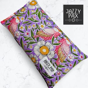 May include: Purple fabric heat pack with a floral pattern featuring pink birds and white flowers. The pack has a label that reads "Jazzy Pax Warm/Cold Therapy Pack".