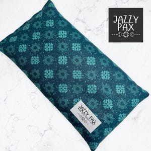 May include: A rectangular, teal-colored aromatherapy pillow with a repeating floral pattern in a lighter teal hue. The pillow features a white label with the text "JAZZY PAX" and additional text and symbols.