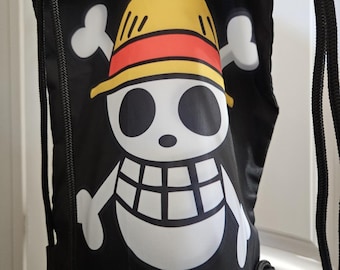 May include: Black drawstring backpack featuring a white skull and crossbones design with a yellow hat and red band. The backpack has black drawstrings and is likely made of a durable fabric, suitable for carrying items.
