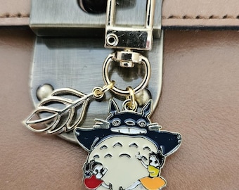 Clip con dije de Totoro en seis estilos diferentes con hojas doradas y clip giratorio para adornar tu objeto favorito.