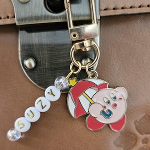 Clip personalizado con Kirby en tres estilos diferentes: paraguas, cantando, con alas y con halo.