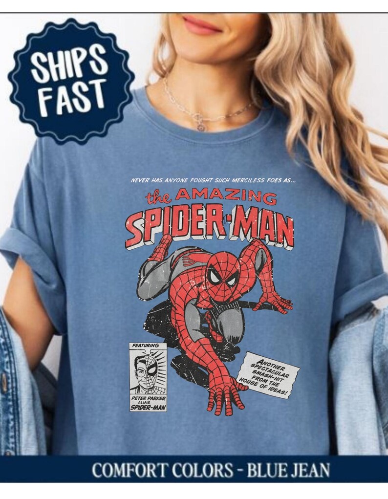 K&ouml;nnte beinhalten: Blaues Jeans-T-Shirt mit einem Vintage-Comic-Grafik von Spider-Man. Das Design enth&auml;lt den Text "the AMAZING SPIDER-MAN" und weitere Comic-Elemente. Das Shirt hat auch den Text "COMFORT COLORS - BLUE JEAN".