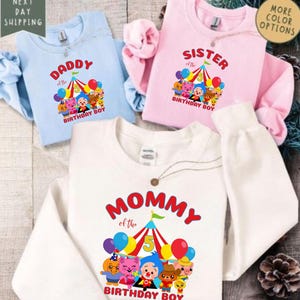 Puede incluir: Tres sudaderas con gr&aacute;ficos tem&aacute;ticos de cumplea&ntilde;os. Una sudadera azul claro dice "DADDY of the BIRTHDAY BOY". Una sudadera rosa dice "SISTER of the BIRTHDAY BOY". Una sudadera blanca dice "MOMMY of the BIRTHDAY BOY".