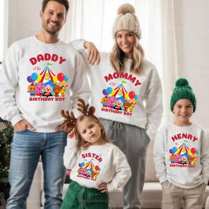Puede incluir: Sudaderas blancas con gr&aacute;ficos coloridos y texto para una familia. Las sudaderas presentan un dise&ntilde;o de carpa de circo con globos y personajes de dibujos animados. El texto incluye "Daddy", "Mommy", "Sister" y "Henry" con "Birthday Boy".